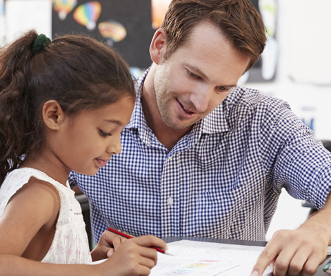 teacher helping student at her desk