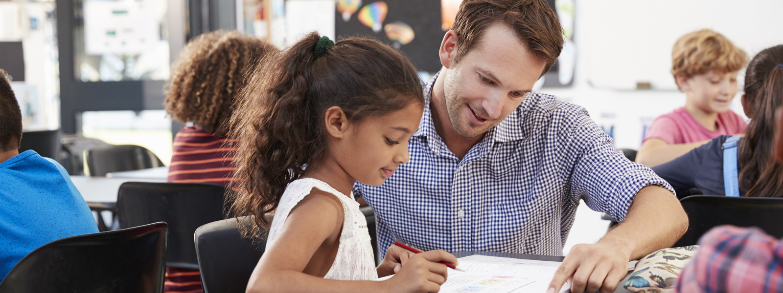 teacher helping student at her desk