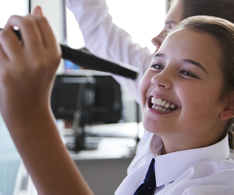 young student writing on a whiteboard cheerfully