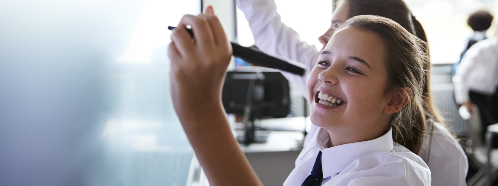 young student writing on a whiteboard cheerfully