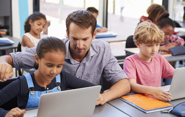 a teacher helping a student at her laptop